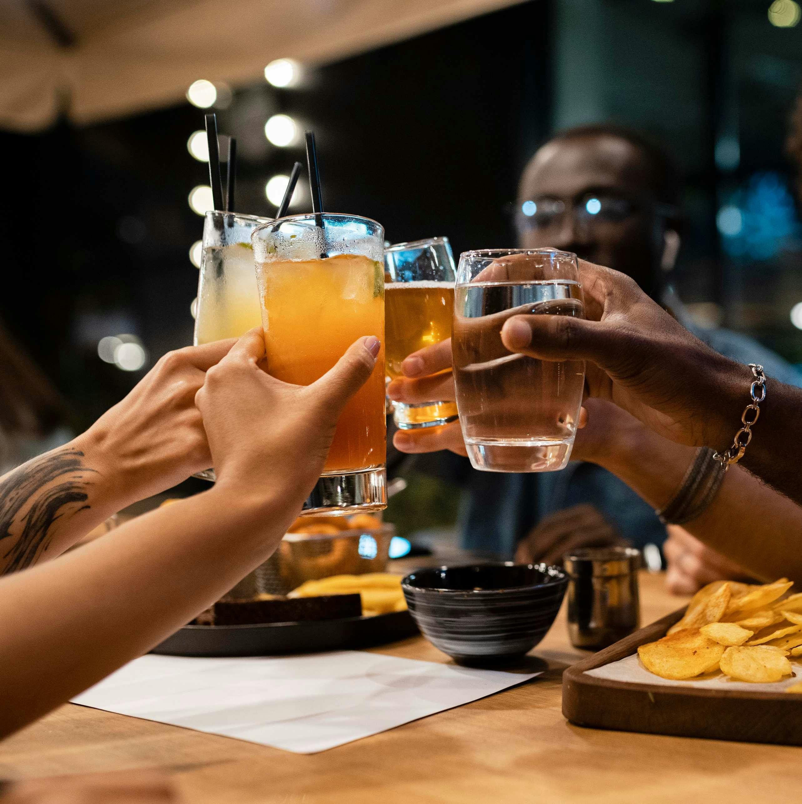Pessoas bebendo e brindando em um bar, enquanto tem uma boa experiência